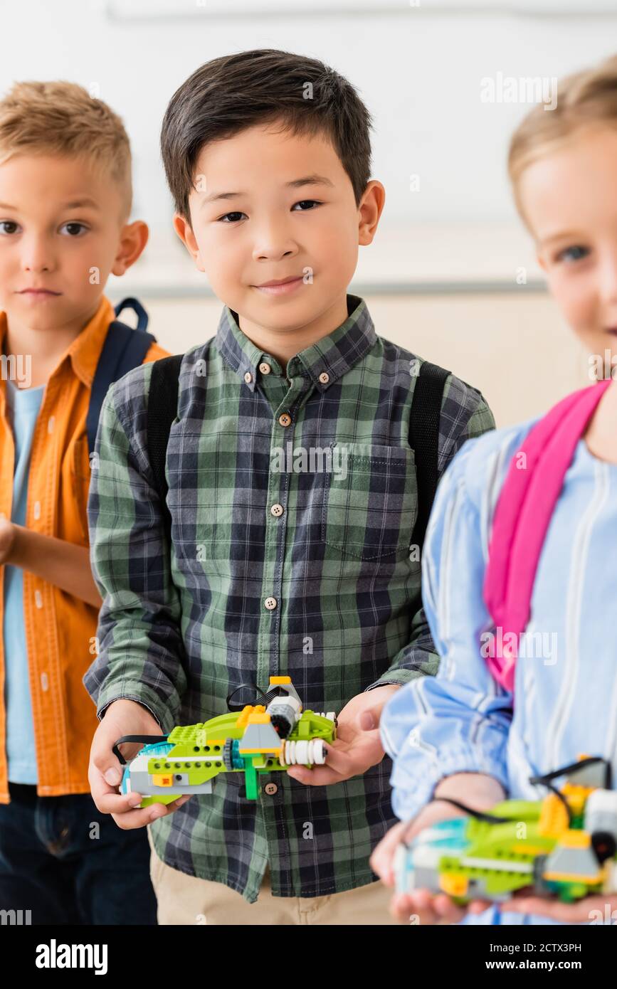 Selektiver Fokus der asiatischen Schuljunge halten Roboter in der Nähe von Freunden in Schule Stockfoto