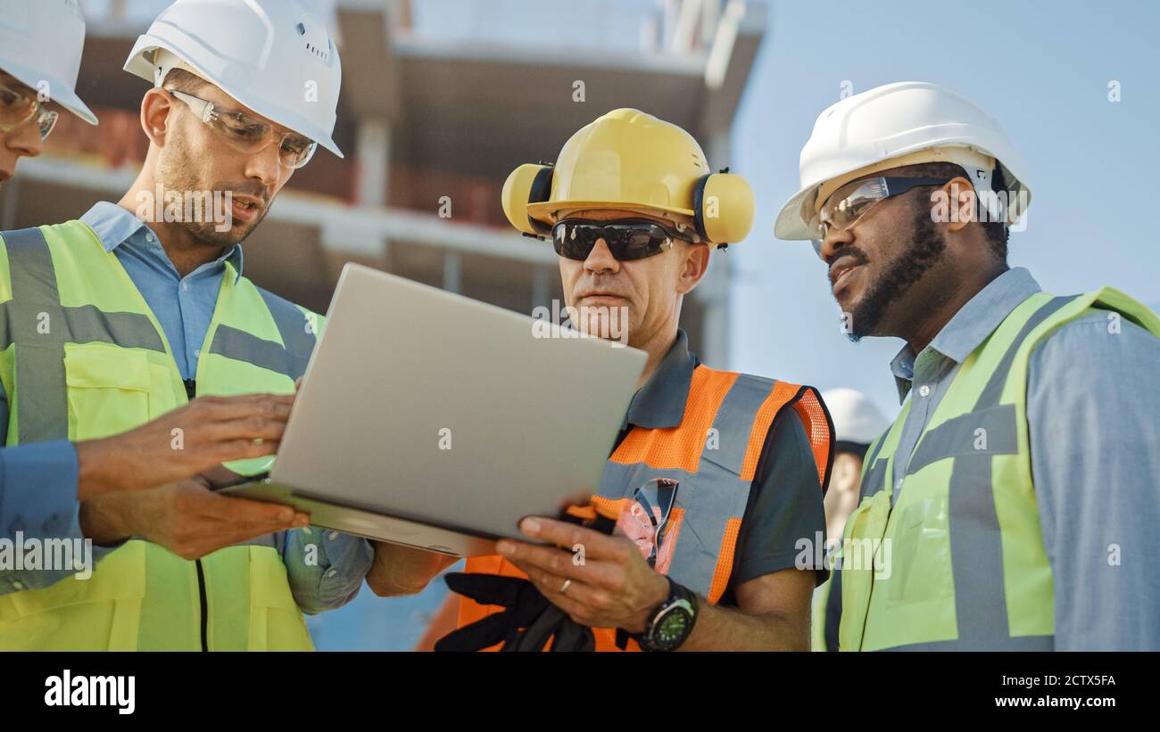 Diverse Team von Spezialisten verwenden Laptop-Computer auf der Baustelle. Immobilienbauprojekt mit Bauingenieur, Architekturinvestor Stockfoto
