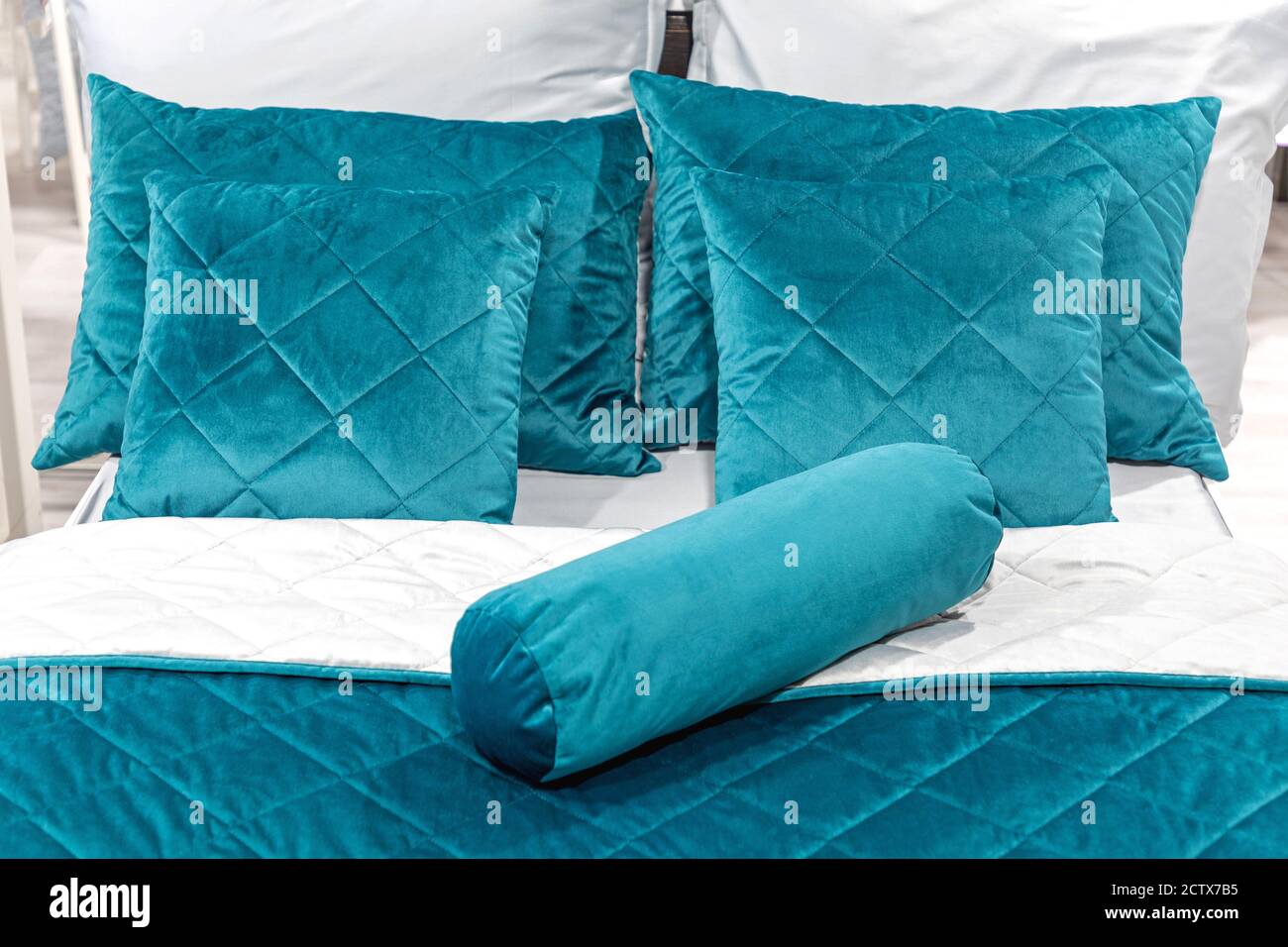 Blaue Plüschkissen im großen Bett Stockfoto