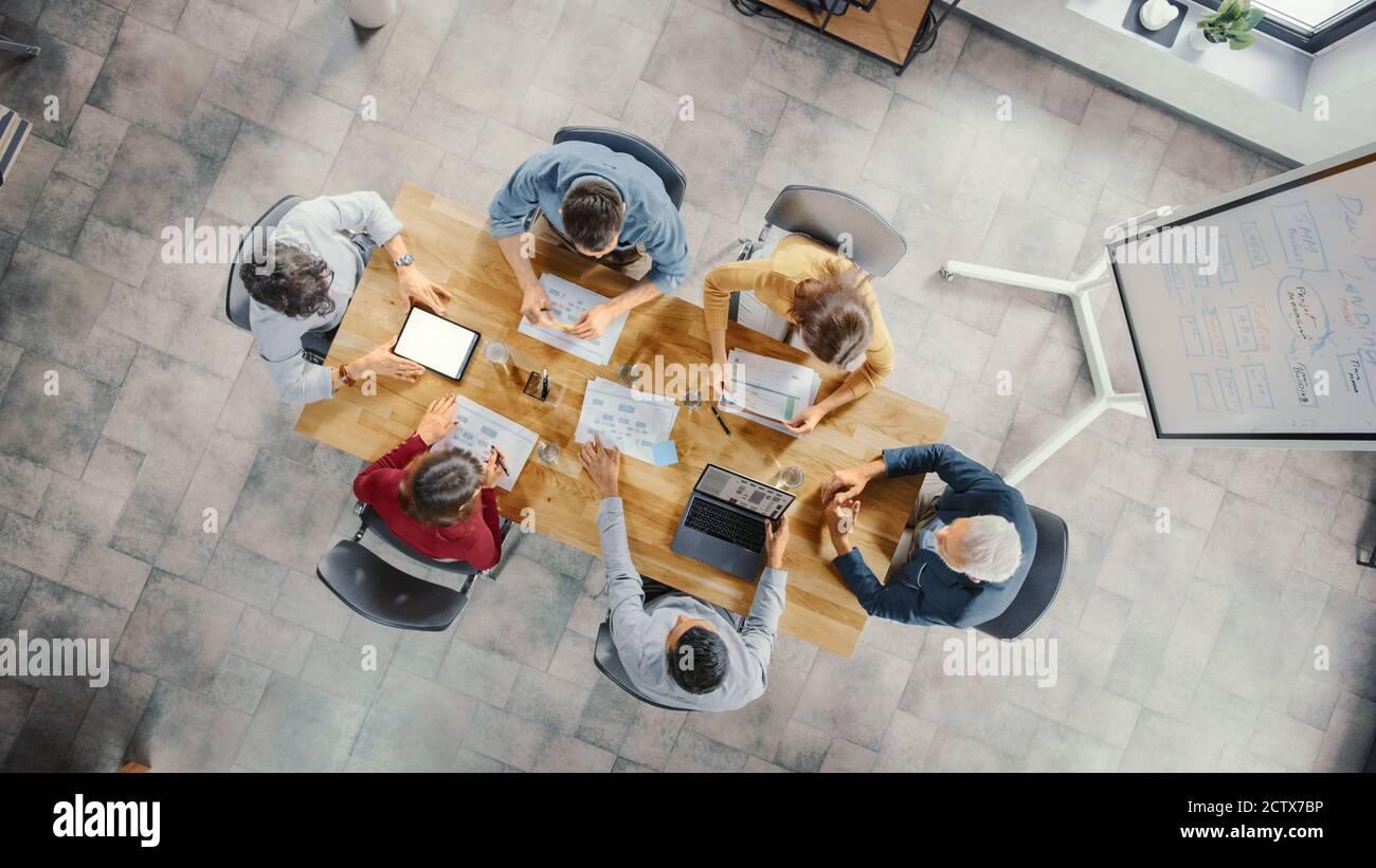 Startup Meeting Room: Team von Unternehmern sitzen am Konferenztisch haben Diskussionen, Probleme lösen, verwenden Sie Digital Tablet, Laptop, Dokumente teilen Stockfoto