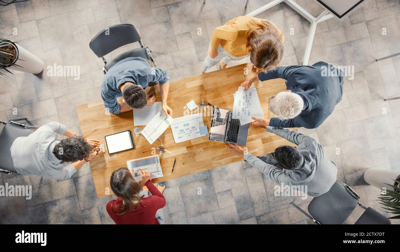 Startup Meeting Room: Team von Unternehmern stehen rund um Konferenztisch haben Diskussionen, Probleme zu lösen, verwenden Sie Digital Tablet, Laptop, Teilen Stockfoto