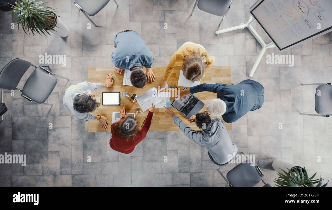 Startup Meeting Room: Team von Unternehmern stehen rund um Konferenztisch haben Diskussionen, Probleme zu lösen, verwenden Sie Digital Tablet, Laptop, Teilen Stockfoto