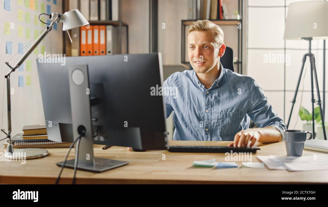 Creative Entrepreneur sitzt an seinem Schreibtisch arbeitet auf Desktop-Computer im stilvollen Büro. Handsome Kaukasischen Mann Verwendet Computer. Im Hintergrund Stockfoto