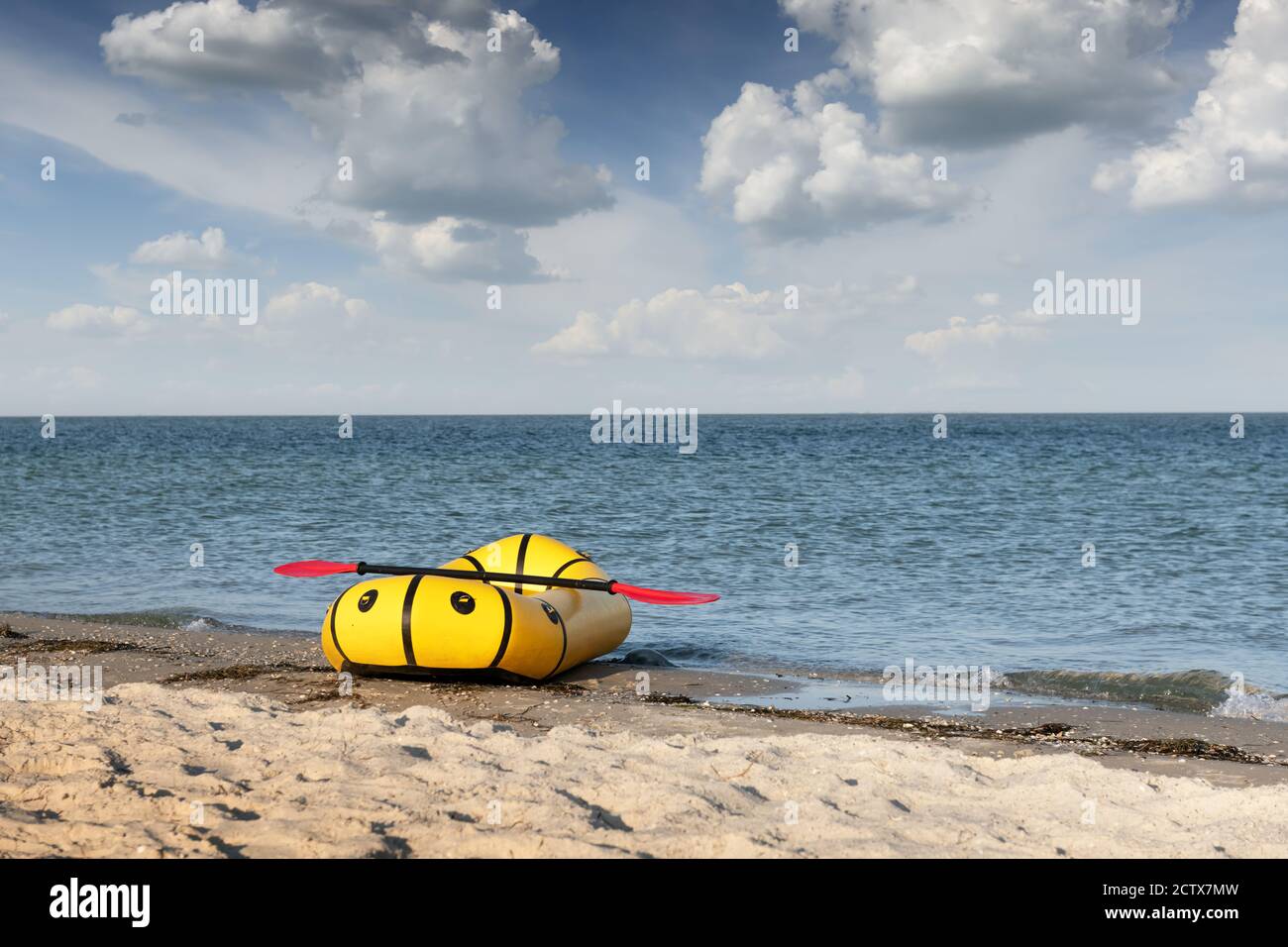 Gelbes Packfloß Gummiboot mit roter Pfanne an einer Küste. Packrafting. Aktives Lebenskonzept Stockfoto
