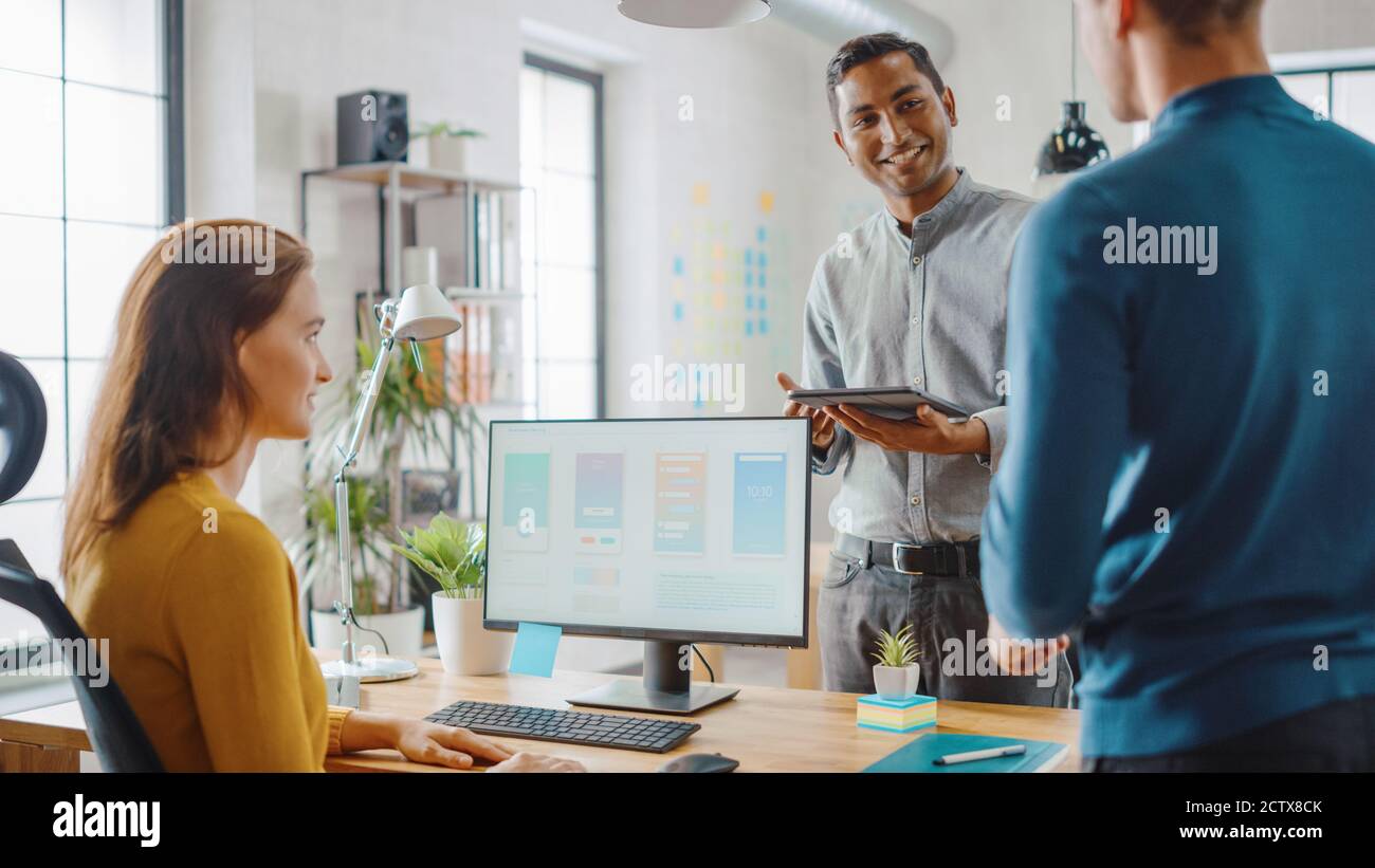 Drei Mobile Software-Entwickler arbeiten an Desktop-Computer, sie diskutieren Smartphone Application Design verwenden Touch Screen Digital Tablet. Modern Und Stilvoll Stockfoto
