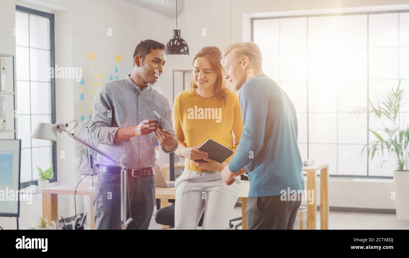 Im Büro: Drei verschiedene Start-up-Unternehmer treffen sich und diskutieren über das Projekt. Digitales Tablet Mit Touchscreen Freigeben. Jung Stockfoto