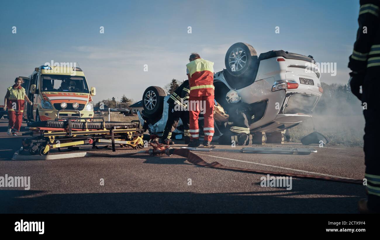 Auf dem Auto Crash Verkehr Unfallort: Sanitäter und Feuerwehrleute Rettung verletzten Opfer im Fahrzeug gefangen. Person Mit Ketschern Extrizieren Stockfoto