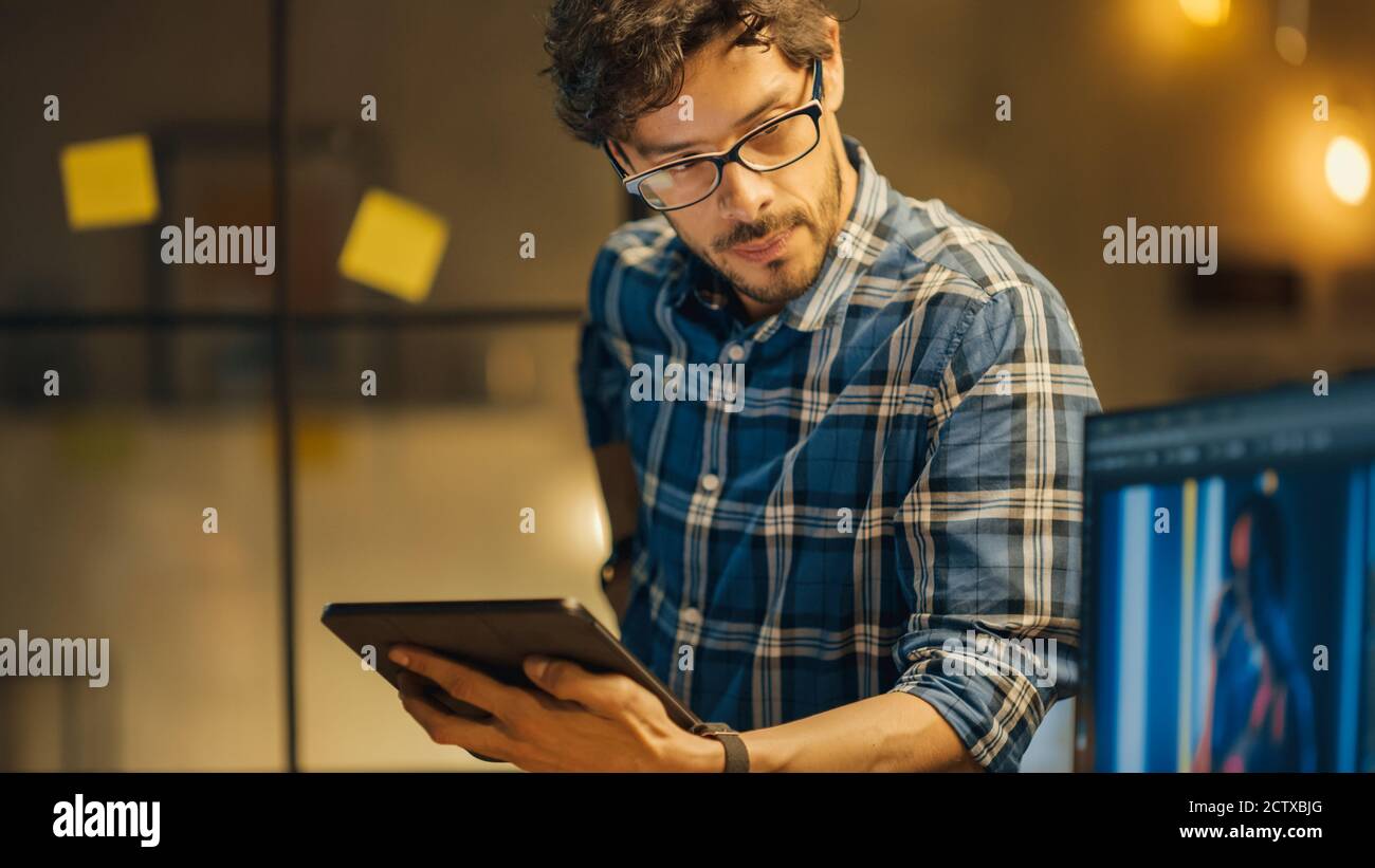 Aufnahme des Creative Younge Photo Editor Specialist, der Tablet-Computer verwendet und Kollegen mit Photo Edit hilft und Ratschläge gibt. Stilvolles Büro im Stockfoto