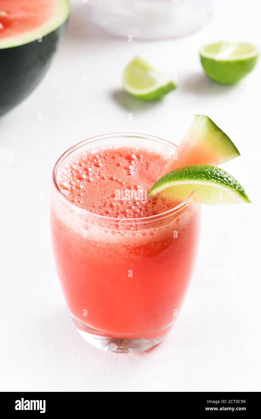 Nahaufnahme von Wassermelonensaft mit Limette in einem Glas auf weißem Stein Hintergrund. Gesundes Sommergetränk. Stockfoto
