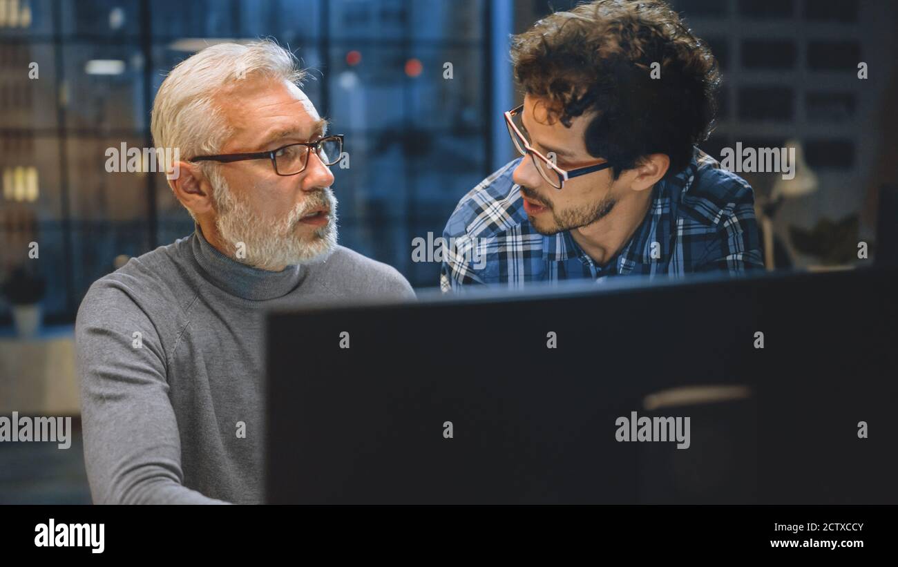 Chief Creative Designer zeigt Desktop-Computer-Bildschirm zu einem jungen Entwickler, sie diskutieren Projekt. Zwei Fachleute, Die Diskussion Führen. Die Richtige Wahl Stockfoto