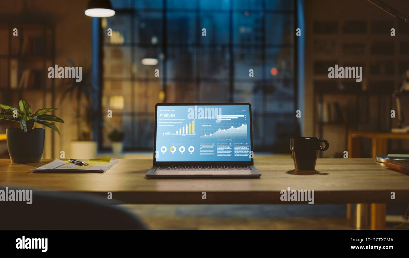 Aufnahme eines Laptops auf einem Schreibtisch mit Statistikdiagramm, Diagramm und verschiedenen Daten, die das Wachstum und den Erfolg des Unternehmens zeigen. Im Hintergrund warme Abendbeleuchtung Stockfoto