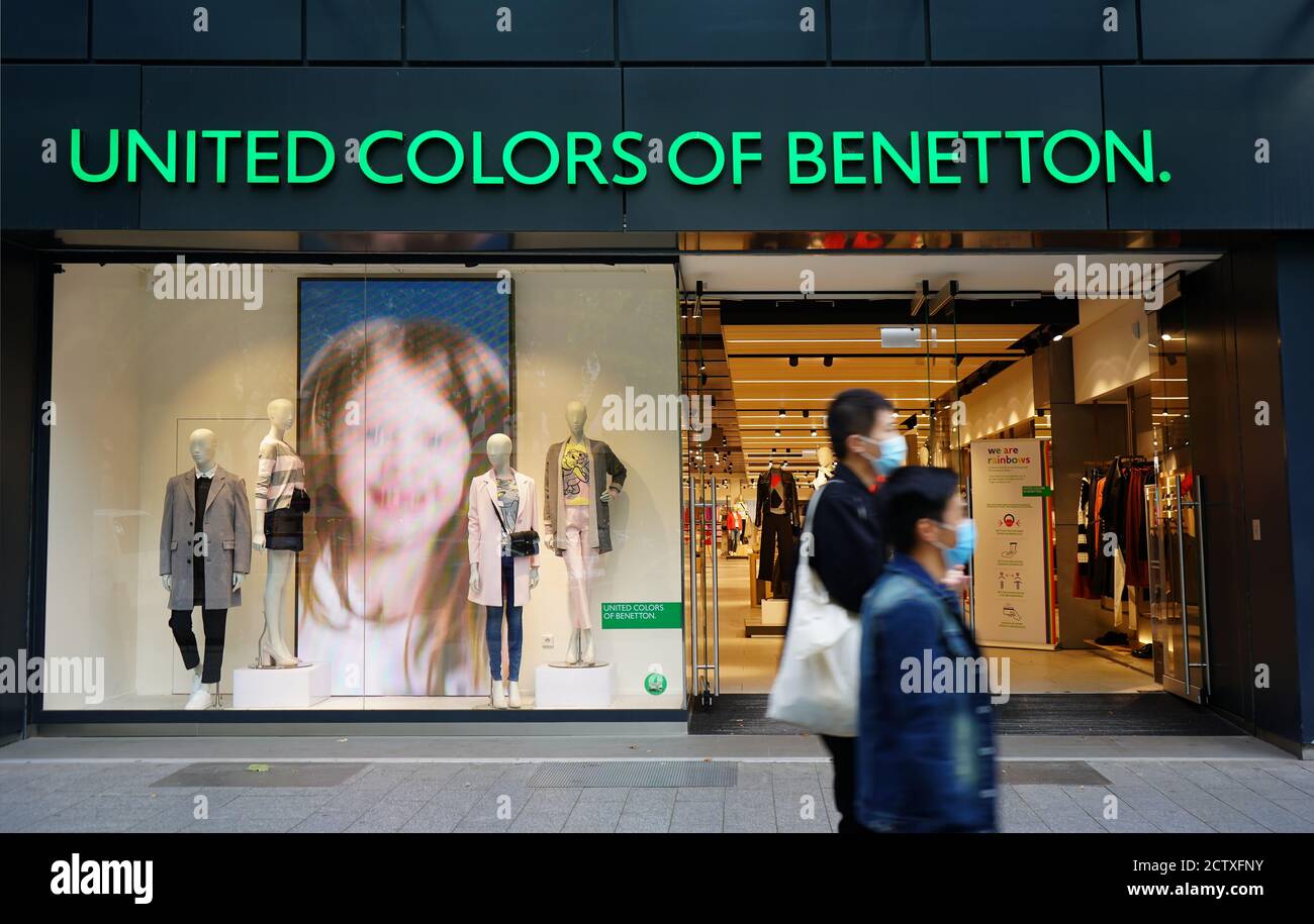 Benetton Store in der Königsallee in der Düsseldorfer Innenstadt. Verschwommene Menschen tragen Masken zu Fuß vorbei. Stockfoto