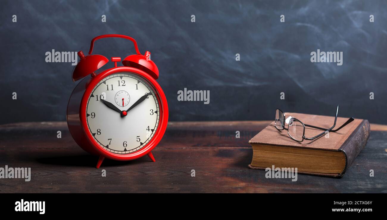 Wecker, alte Bücher und Lesebrille auf einem Holztisch, Kreidetafel Hintergrund. Zeit zum Lesen, Studium, Bildungskonzept. 3d-Illustration Stockfoto