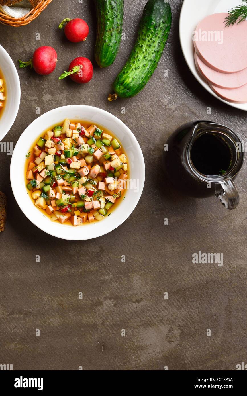 Traditionelle kalte russische Okroshka-Suppe mit Wurst, Gemüse und Kvass auf braunem Steingrund mit Freitextraum. Leckeres Sommergericht zum Abendessen Stockfoto