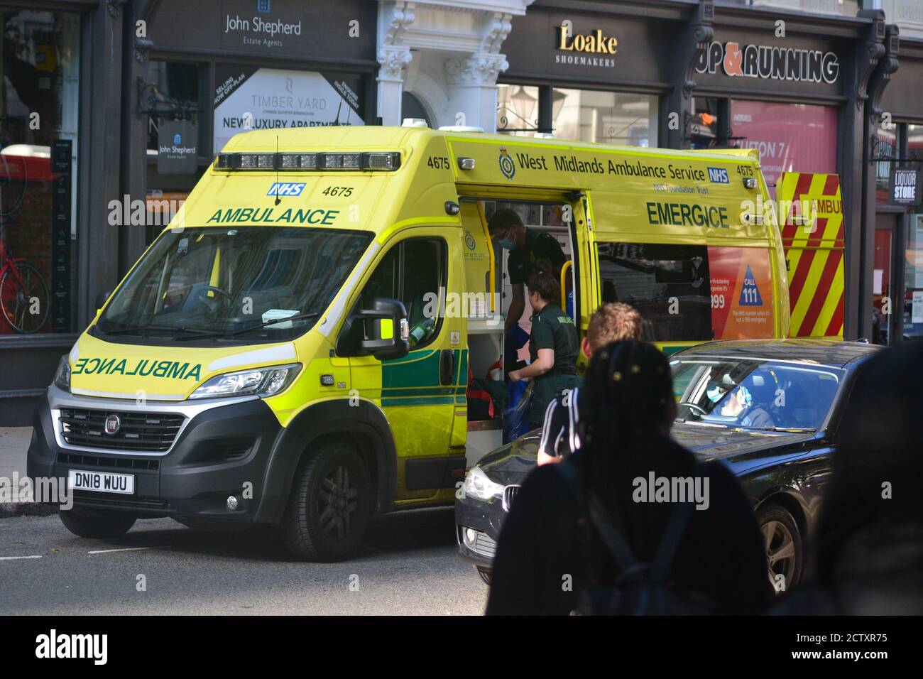 West Midlands Ambulanzdienst in der Colmore Row in Birmingham, der einen Mann, der von der Polizei wegen Gewalt festgenommen wurde, behandelt Stockfoto