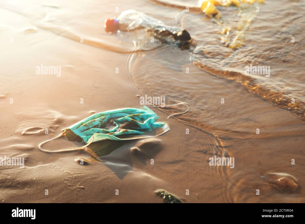 Medizinische Gesichtsmaske und Plastikmüll im Wasser an der Küste. Umweltverschmutzung seit Coronavirus covid-19 Pandemie Stockfoto