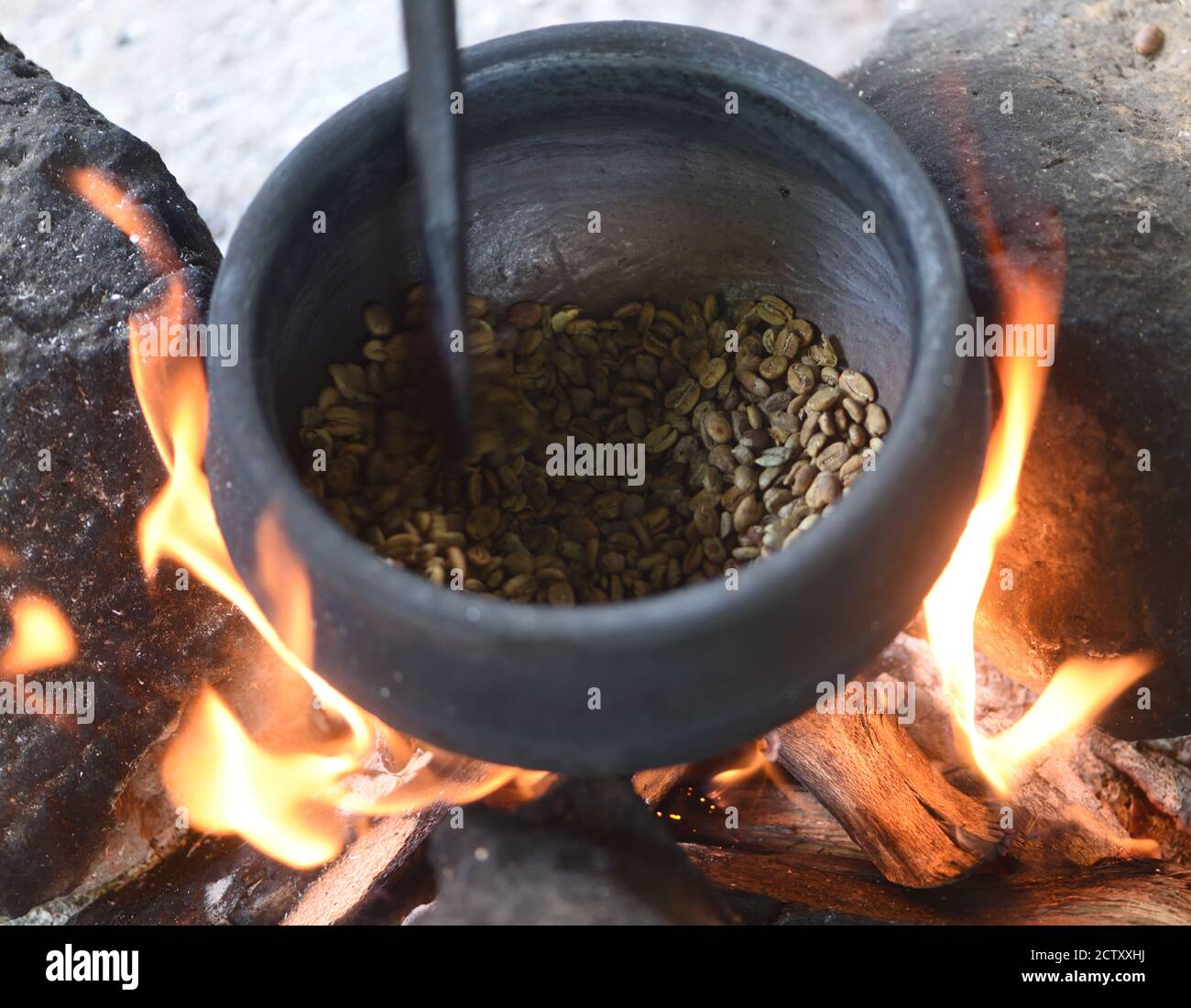 Lokal angebauter Kaffee, der über einem offenen Holzfeuer in einer schweren Eisentopf geröstet wird. Moshi, Tansania. Stockfoto