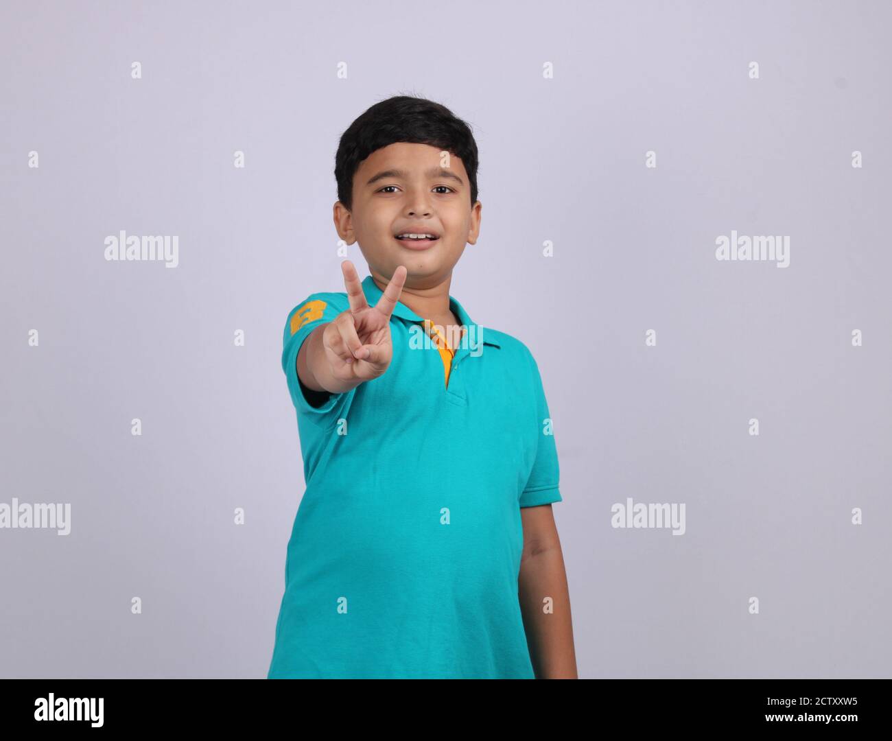 Niedlich und smart indischen Jungen Anzeige Pose. Es ist ein nach vorne gerichtete Foto, wo Junge sieht zuversichtlich und drückt sich mit der Hand Geste. Stockfoto