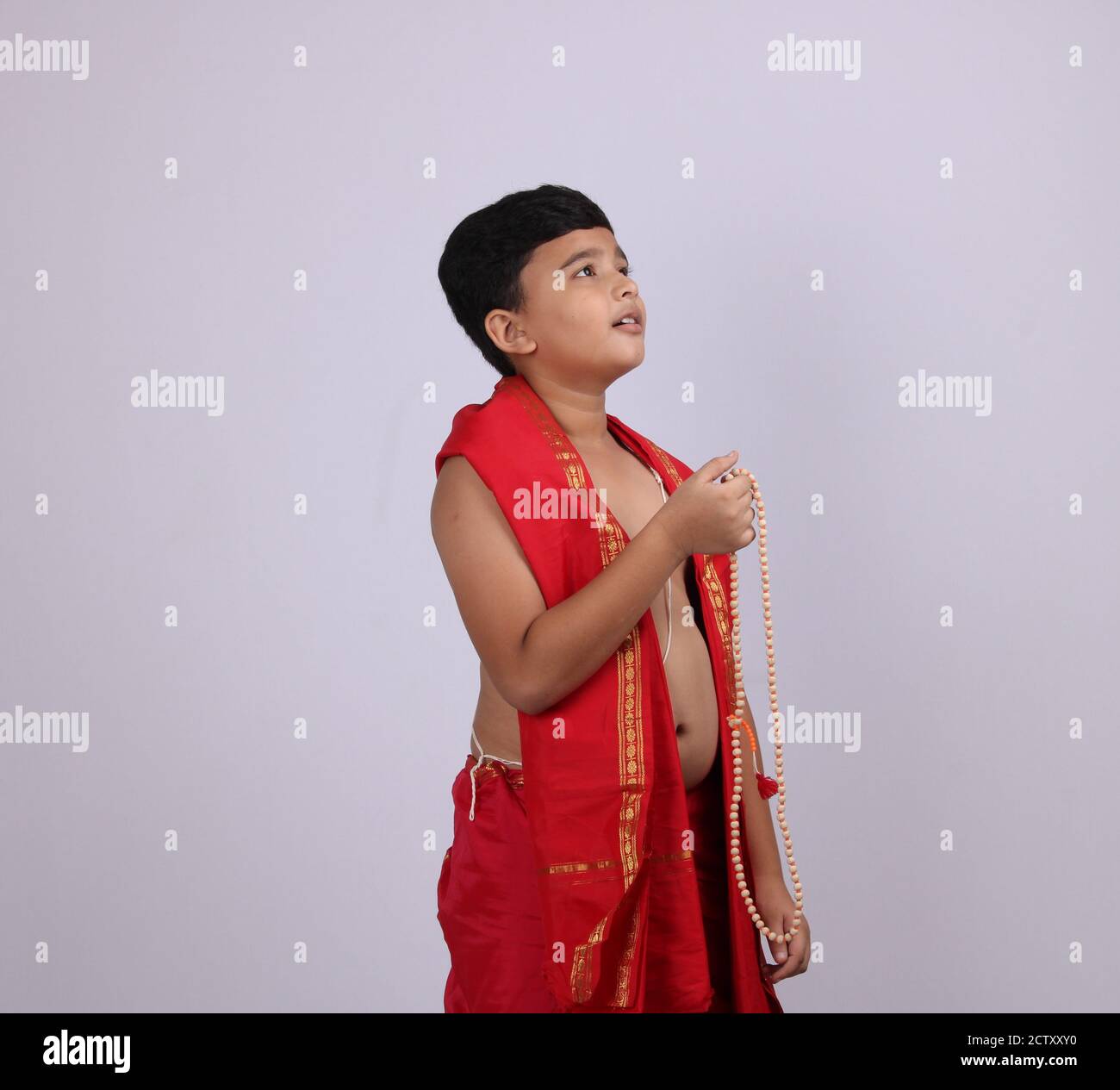 Niedlichen Jungen in indischen ethnischen tragen chanting Gottes Namen / jaap. Mit Rosenkranz Zeichenfolge Gebet Perlen oder japamala. Stockfoto