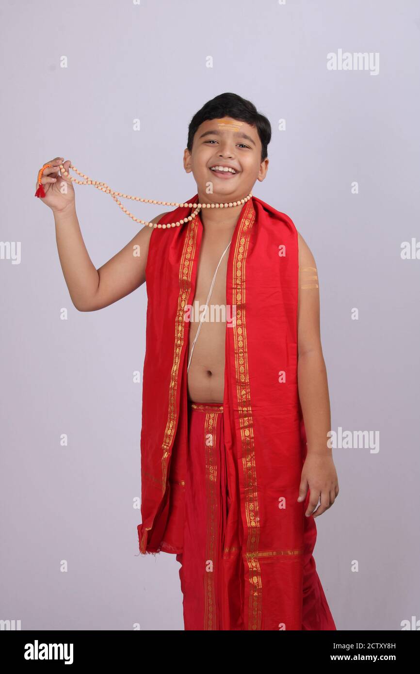 Indischer Junge in ethnischer Kleidung zeigt seinen Rosenkranz oder Kette von Gebetsperlen mit Lächeln. Stockfoto