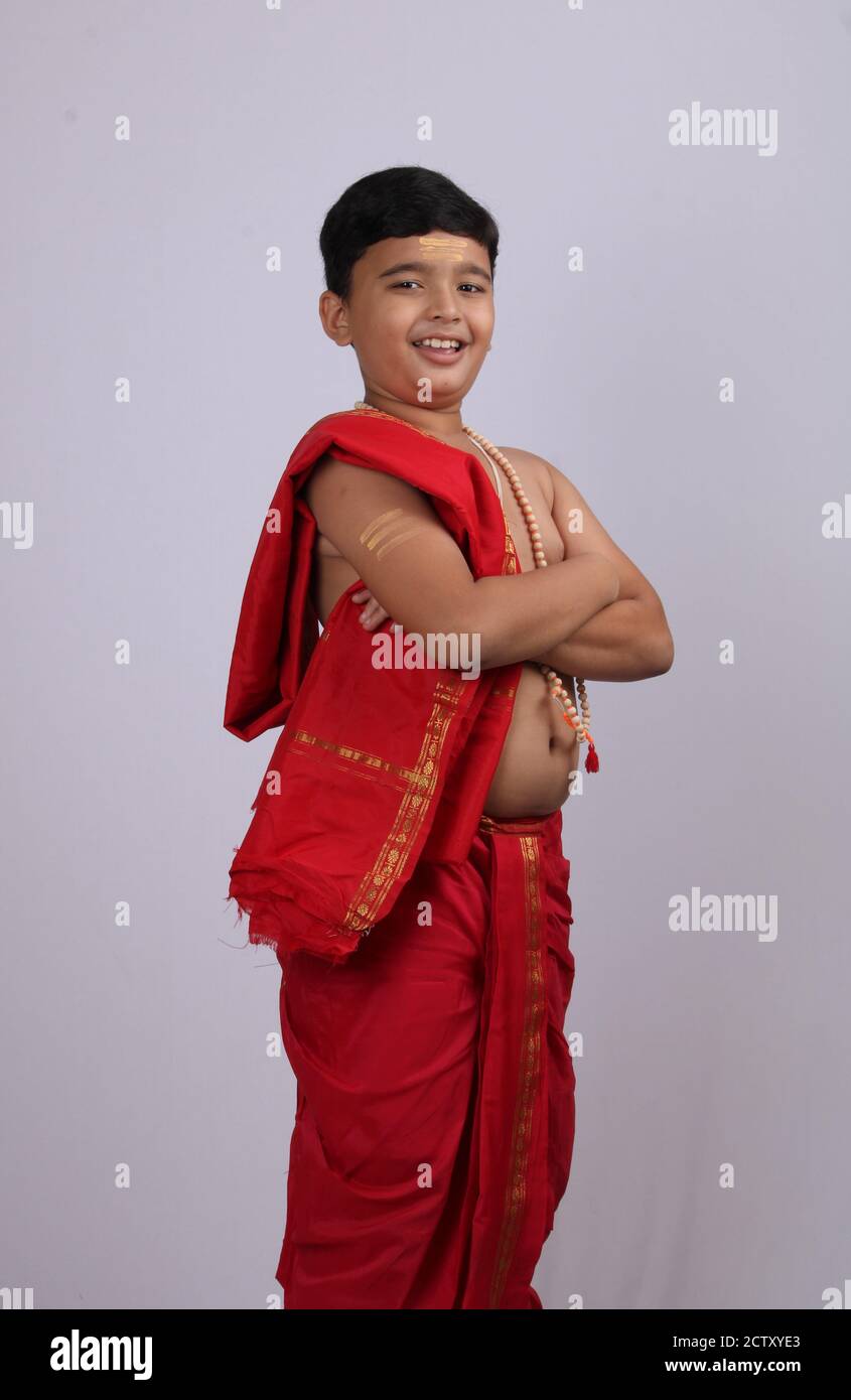 Cute indischen Jungen in traditioneller Kleidung posiert mit foldel hatte Geste. Stockfoto