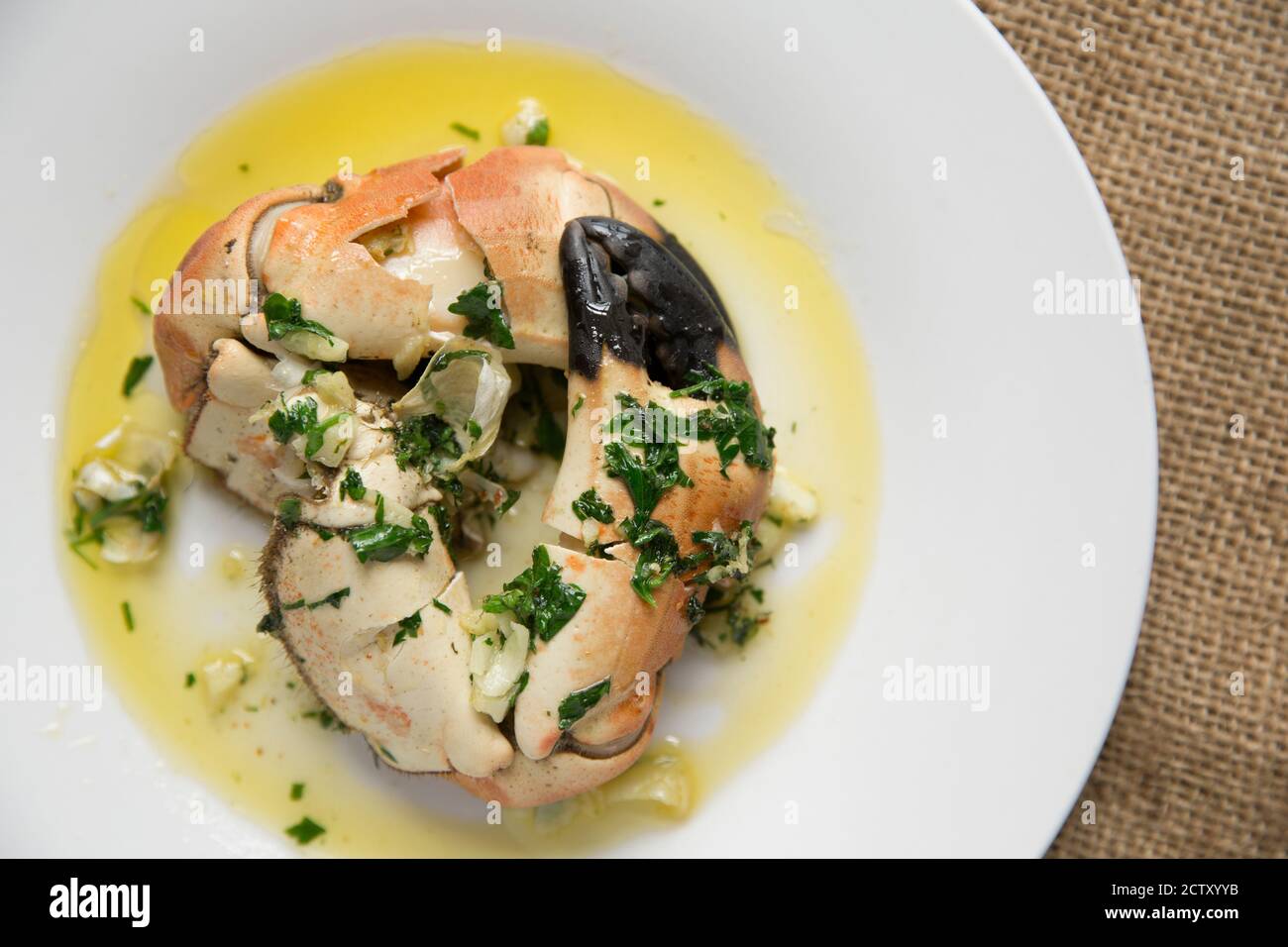 Zwei gekochte, geknackte Krabbenkrallen aus einer braunen Krabbe, Cancer Pagurus, die mit Butter, Knoblauch und Petersilie serviert wurden. Dorset England GB Stockfoto