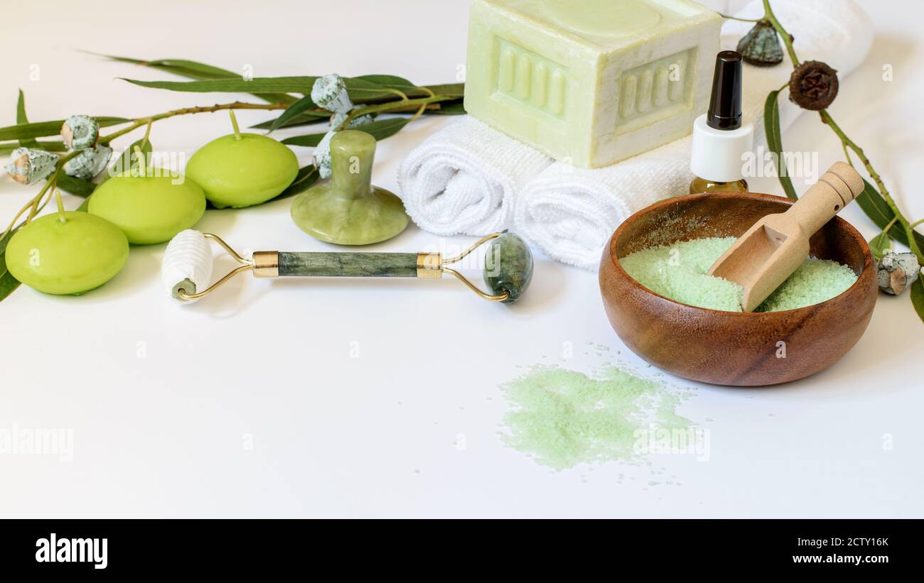 Eukalyptusprodukte Seife, Salz, Kerzen auf weißem Hintergrund. Chinesische Werkzeuge gua Sha, Jade Juwel und Roller für die Gesichtspflege. Gesunder Lebensstil, Aromath Stockfoto