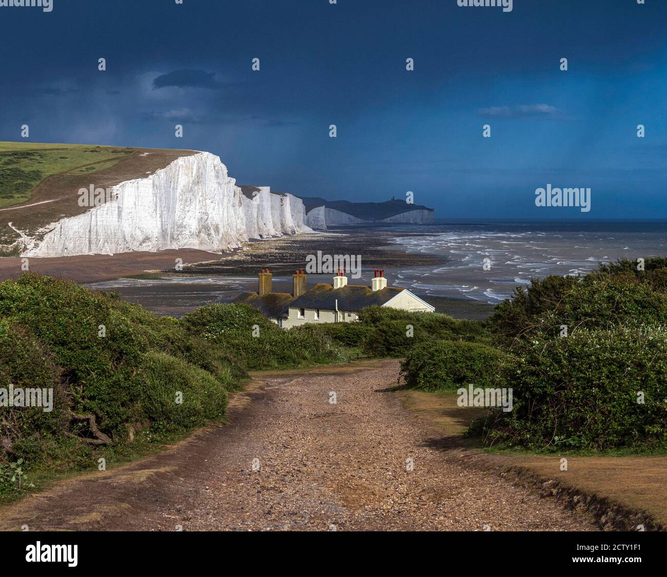 Seven Sisters Kreidefelsen am Beachy Head mit Küstenschutzhütten im Vordergrund und einem herannahenden Sturm, East Sussex, England Stockfoto