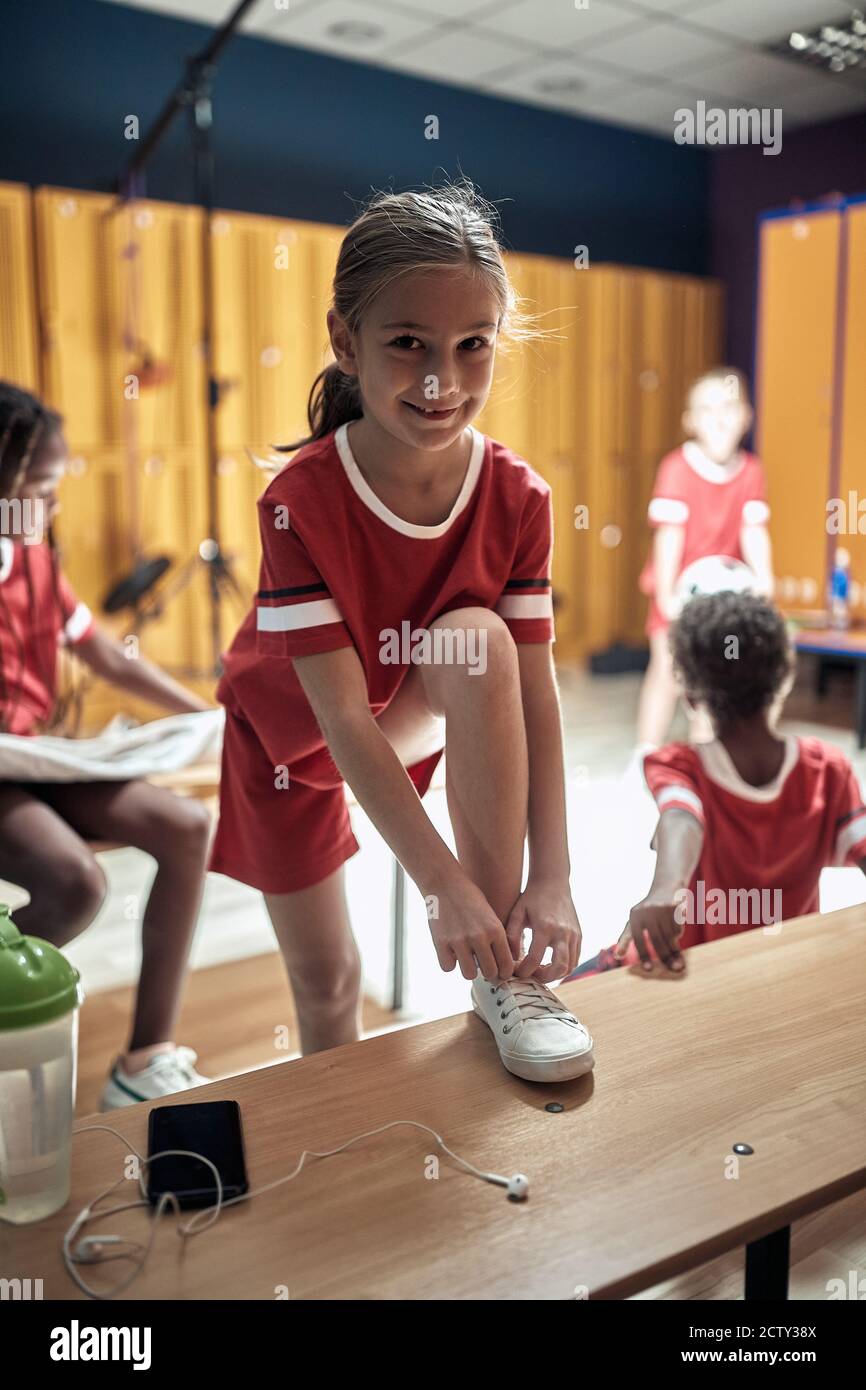 Ein kleines Mädchen posiert in einem Umkleideraum vor einem Schulung Stockfoto