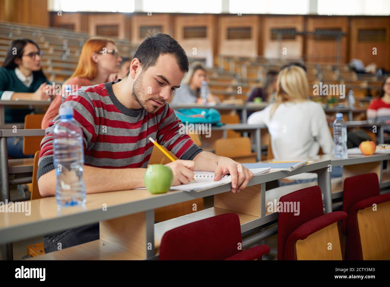 Männlicher Student konzentrierte sich auf die Lektion bei der Vorlesung in Das Klassenzimmer der Universität Stockfoto