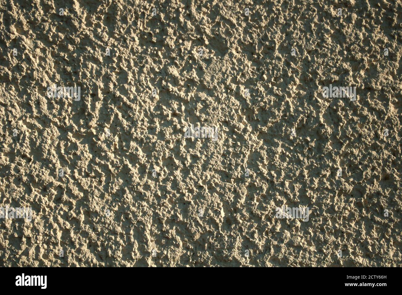 Grobkörniger Hintergrund, hellgelbe Wandoberfläche, aufgenommen an einem sonnigen Tag, harte Schatten Stockfoto