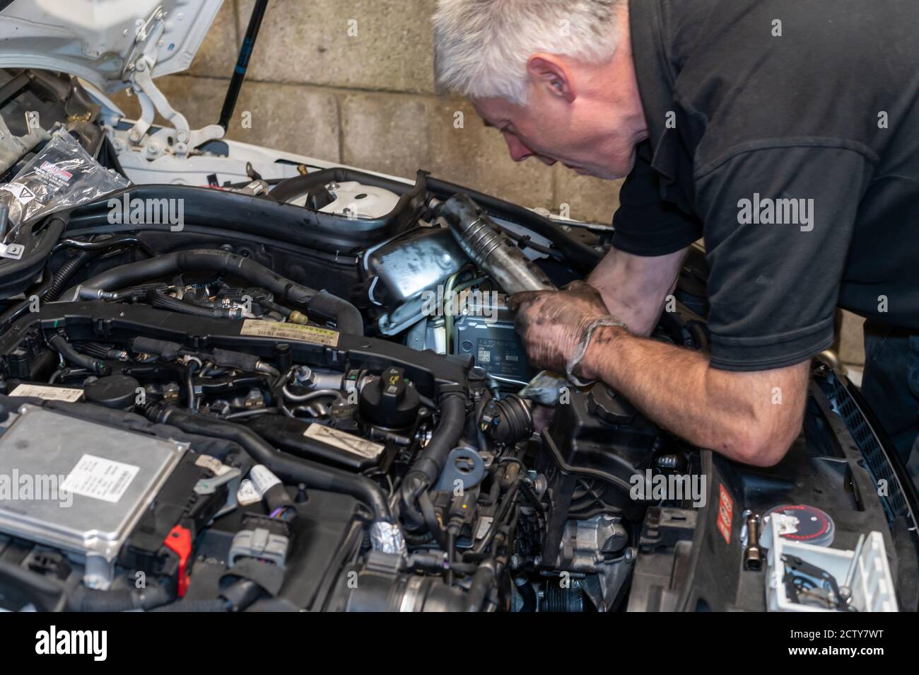 Mechaniker, der am Motorraum arbeitet, um eine Ölundichtigkeit zu beheben. Stockfoto