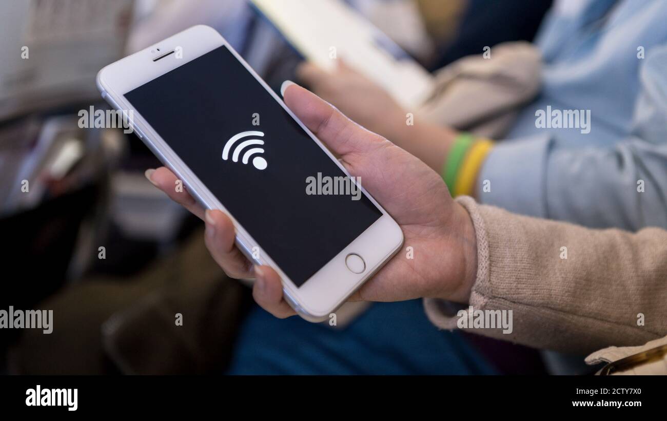 Asiatische Frau hält das Smartphone und erhalten die kostenlose WiFi in einem Flugzeug Reisen. Reisende setzen sich mit dem Telefon ins Flugzeug Stockfoto
