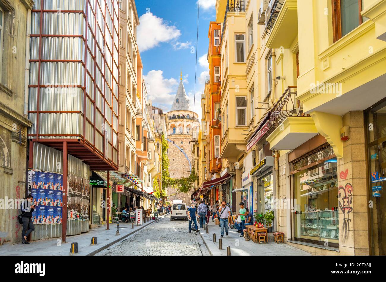 Eine bunte, belebten Straße von Cafés, Geschäften und eine streunende Katze mit der Galata Turm hinter, in Istanbul, Türkei. Stockfoto