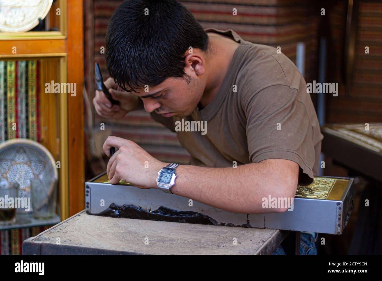 Damaskus ,Syrien 03/27/2010: Nahaufnahme eines jungen Künstlers bei der Arbeit. Er schnitzt sorgfältig eine Kupferplatte mit traditionellen Dekorationen mit Hammer Stockfoto