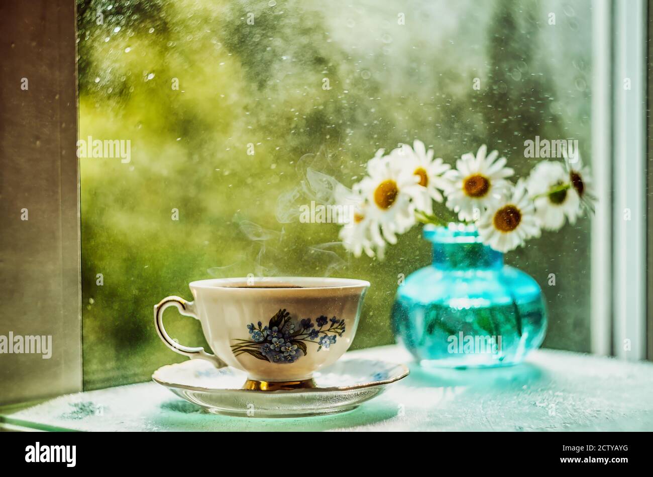 Heißer Tee und sommerlicher Duft von Gänseblümchen auf der Fensterbank Stockfoto