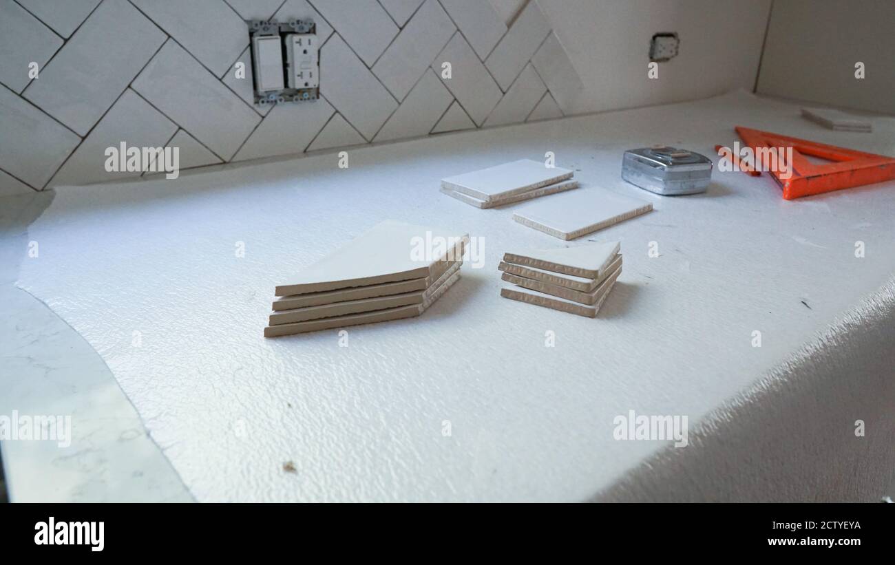 Home Improvement Project - Installation von weißen Keramikfliesen als Küche backsplash. Stockfoto