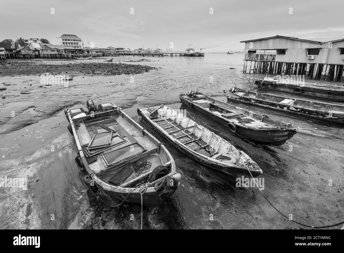 Hafenblick von einem der Clan-Anlegestellen im historischen George Town, Penang, Malaysia - Chew Jetty. Holzboote liegen bei Ebbe in bewölktem regnerischem Wetter Stockfoto