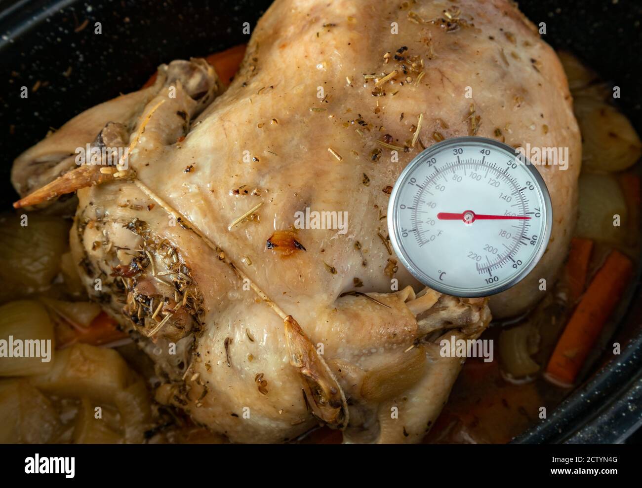 Messung der Innentemperatur des im Ofen gebackenen Hähnchens. Fleisch-/Instant-Read-Thermometer zur Messung der lebensmittelsicheren Temperatur. Ganzes Huhn in schwarzer Pfanne. Stockfoto