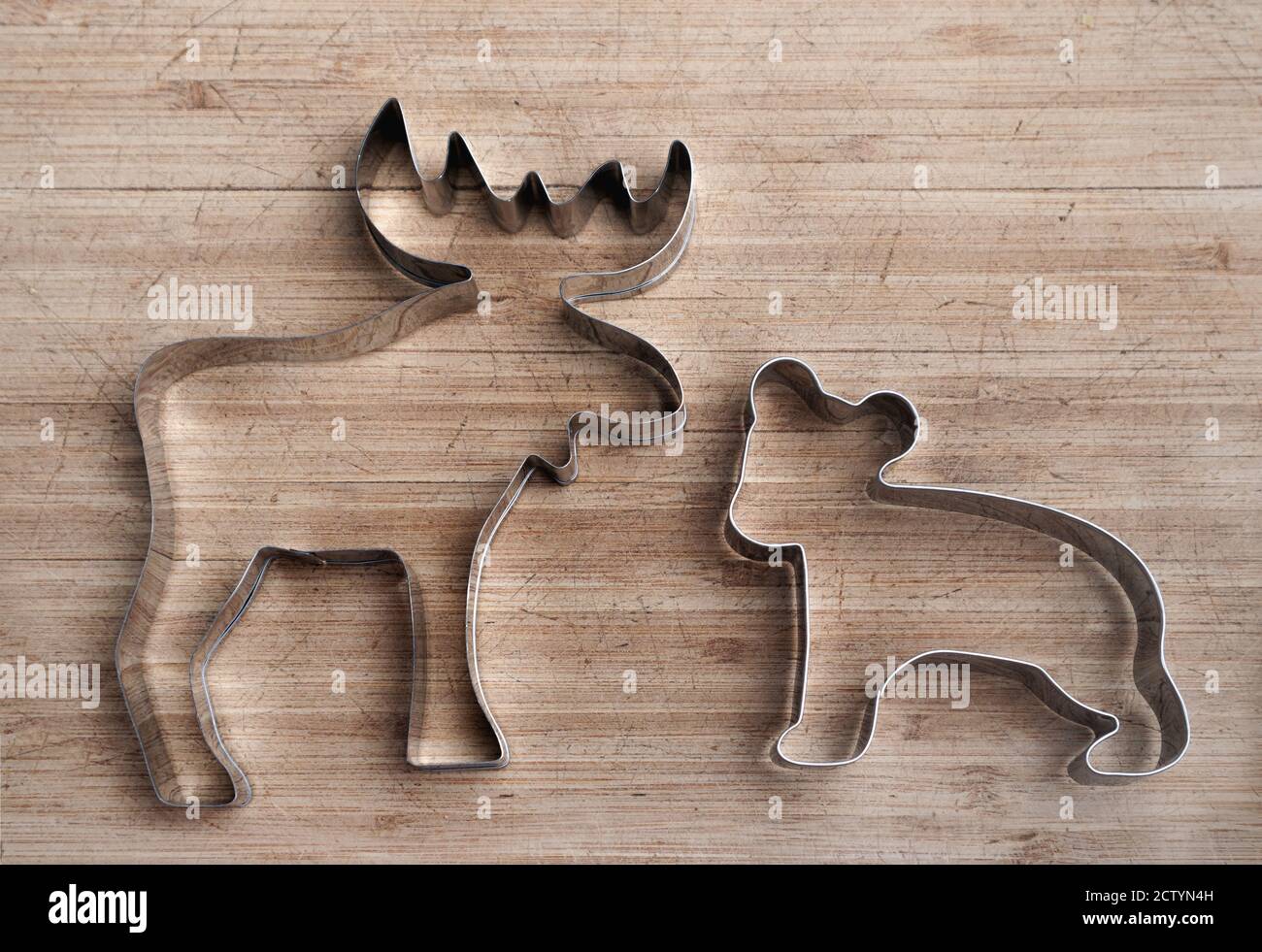 Elch- und Bärenform aus Edelstahl auf Holzbrett. Ausstechform für Tiere. Patriotisches Symbol Kanadas. Silberner Umriss. Stockfoto