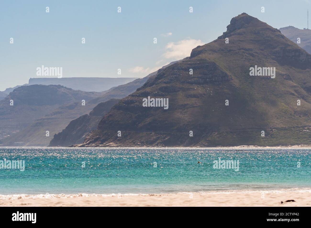 Strandlandschaft mit weißem Sand, türkisblauem Meer oder Meer und Bergen im Hintergrund in Kommetjie, Kapstadt, Südafrika Stockfoto