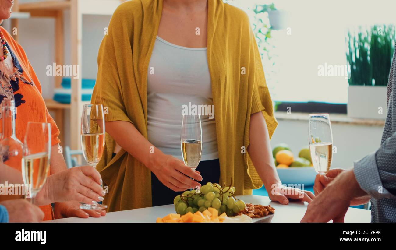 Glückliche Großfamilie bei einem Glas Wein Champagner. Menschen von zwei Generationen reden, sitzen um den Tisch toasten und feiern eine Veranstaltung trinken ein Glas Weißwein. Stockfoto