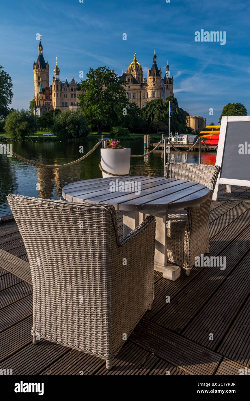 Leere Stühle im Cafe mit einem schönen Schloss in Schwerin im Hintergrund. Stockfoto