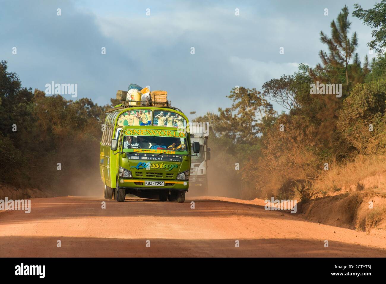 Ein farbenfroher Bus fährt auf einer staubigen Straße in ländlicher Umgebung Kenia Stockfoto