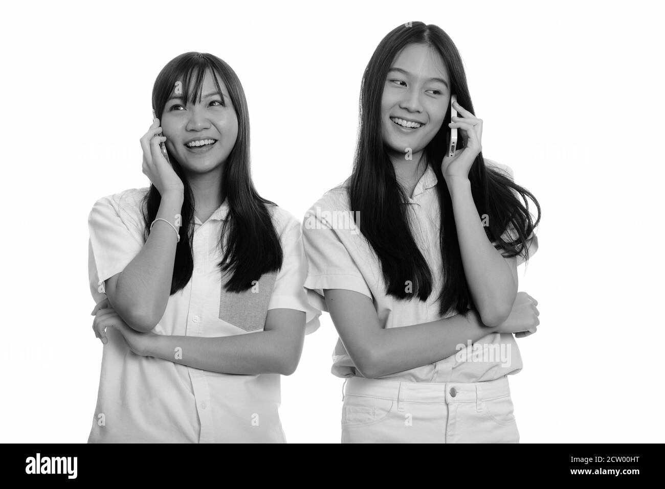 Zwei junge gerne asiatische Mädchen lächelnd und Gespräch am Handy zusammen Stockfoto