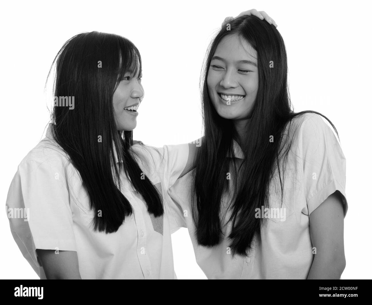 Zwei junge gerne asiatische Mädchen lächelnd und ihr Freund auf den Kopf klopfen Stockfoto