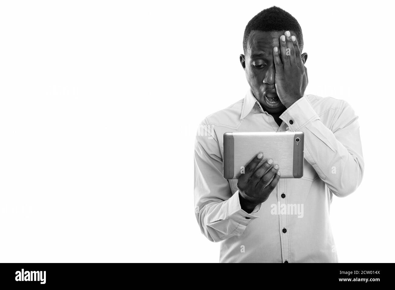 Studio shot von jungen schwarzen afrikanischen Mann mit digitalen tablet, während für Gesicht und geschockt Stockfoto