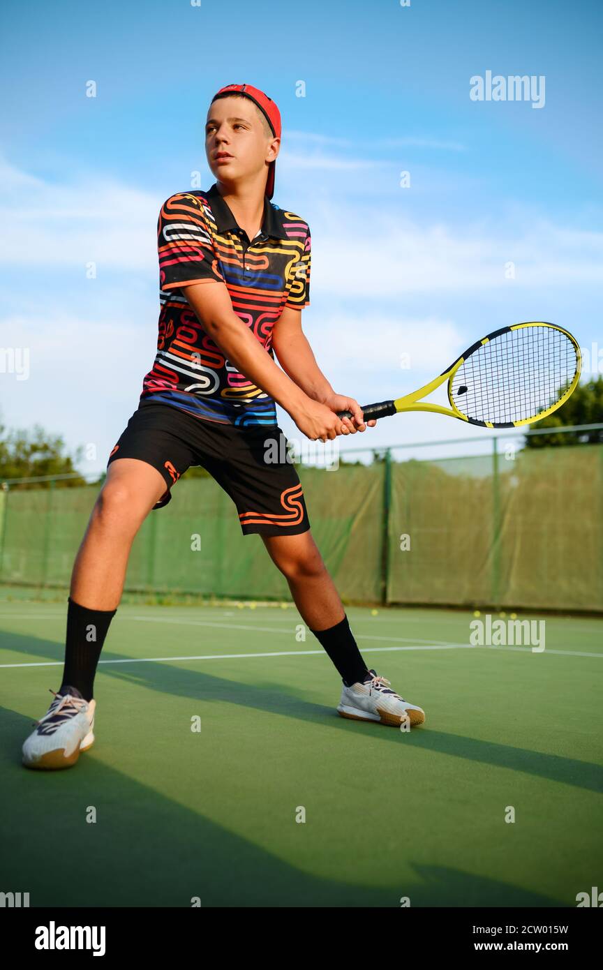 Junger männlicher Tennisspieler mit Schläger trifft den Ball Stockfoto