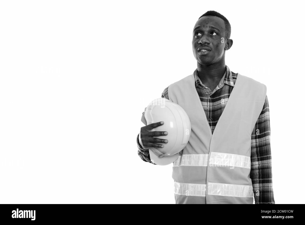 Studio shot von jungen schwarzen afrikanischen Mann Bauarbeiter zu denken, während Holding Schutzhelm Stockfoto