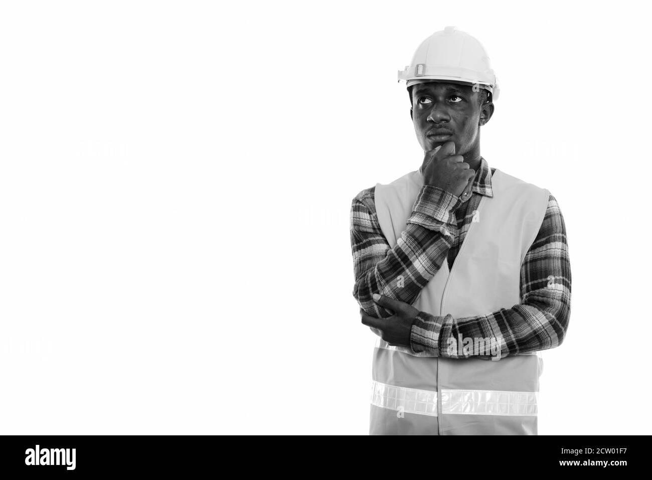Studio shot von jungen schwarzen afrikanischen Mann Bauarbeiter zu denken, während die Suche nach Stockfoto